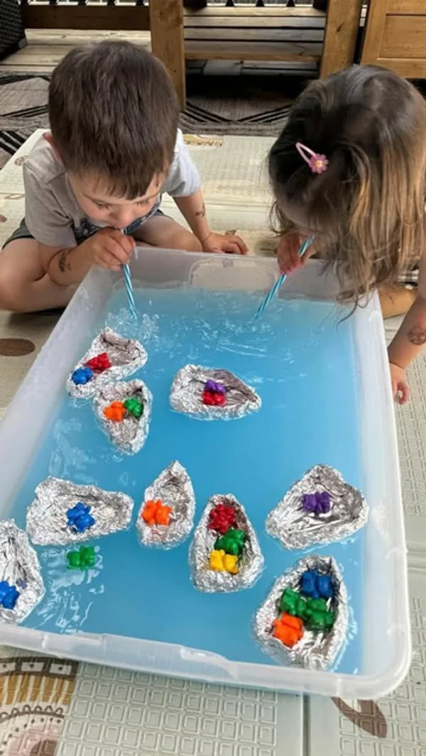 Children blowing boats across water